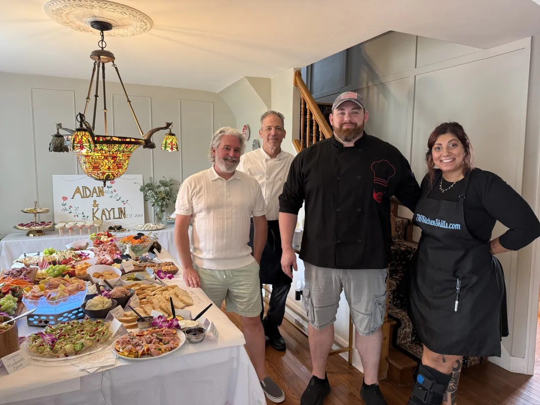 Chef Michael with guests in front of a catered spread