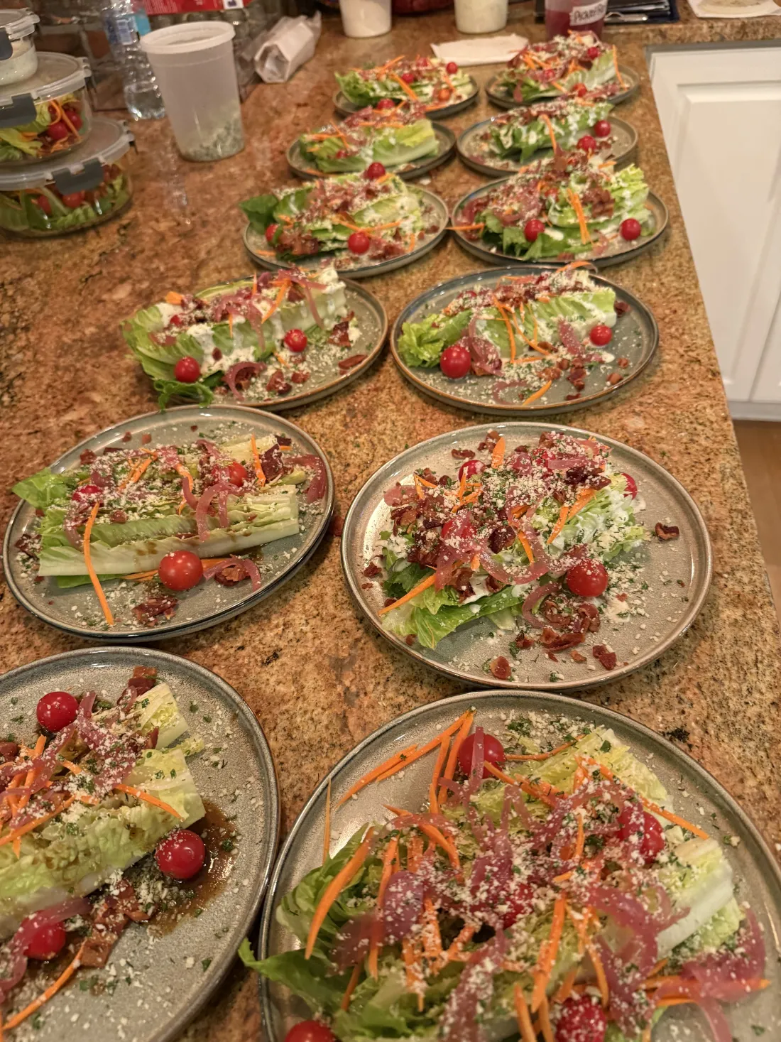 Plated wedge salads lined up on a counter for a dinner party